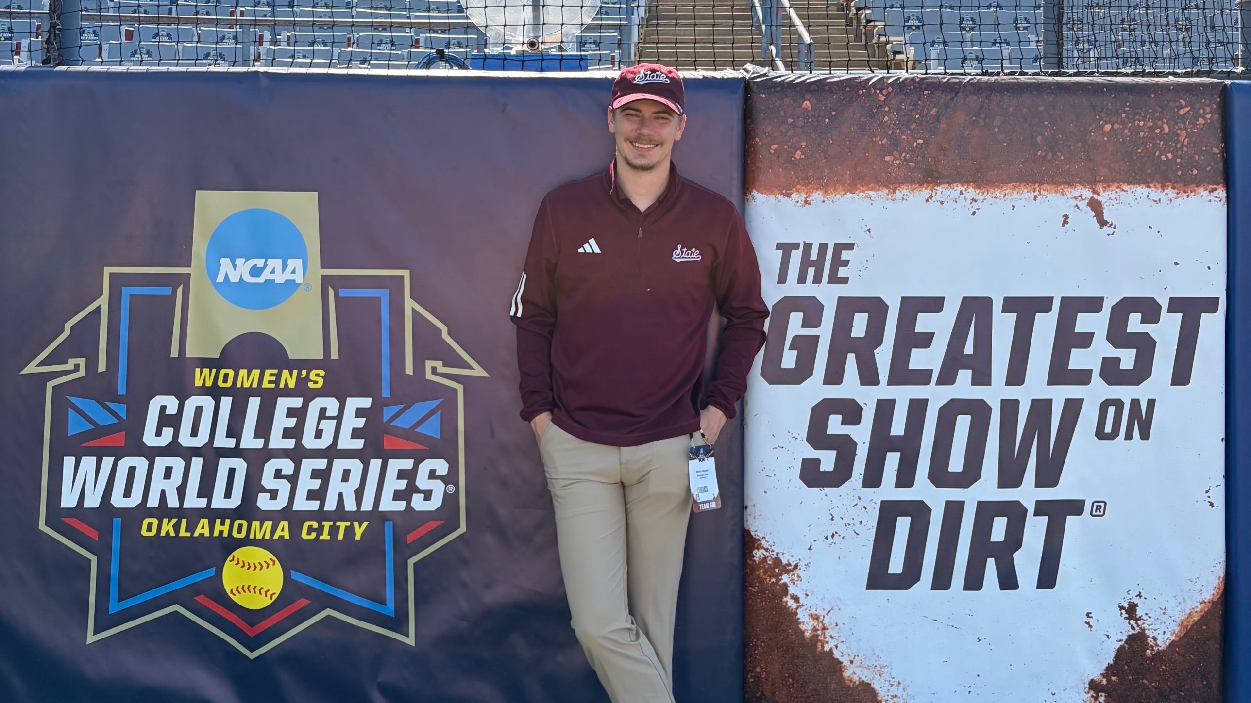 Brian Ogden, director of communications for MSU Athletics, stands in front of a Women’s College World Series banner at the stadium in Oklahoma City